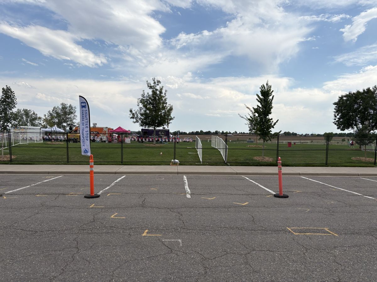 Tribute Fencing & Barricade black welded wire fence panels around a field event with food trucks and tents